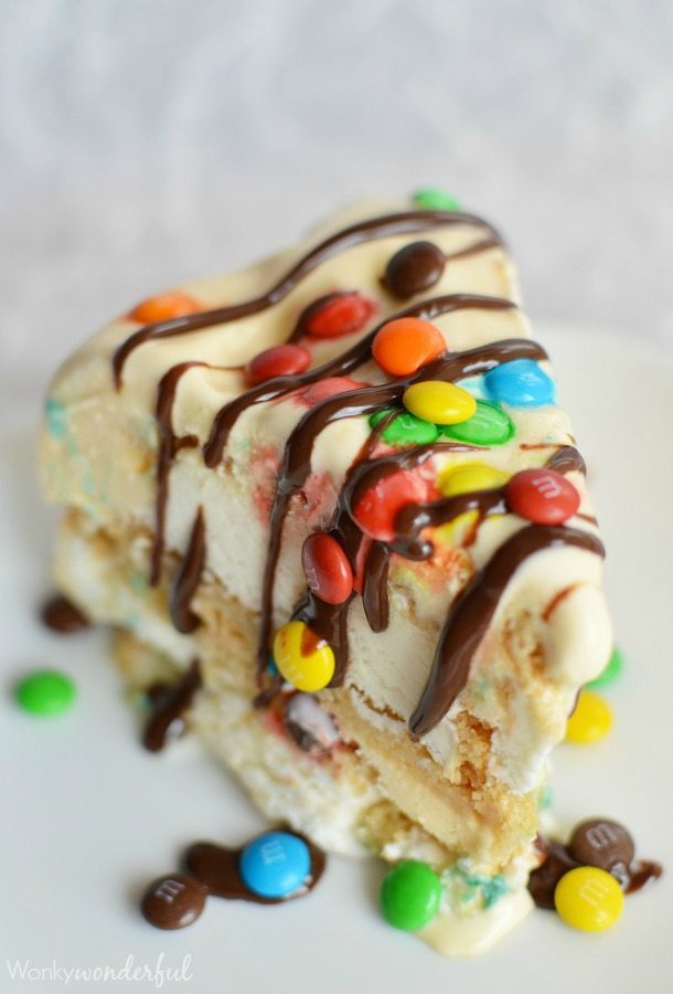 slice of ice cream cookie cake drizzled with chocolate and mini m&m candies