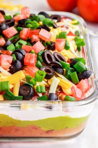 layered dip in clear glass casserole dish