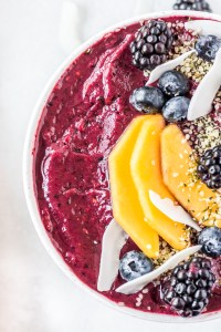 purple puree topped with fruit in white bowl