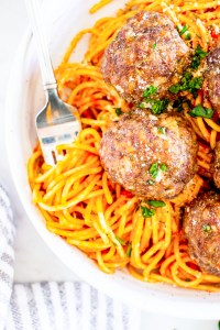 meatballs on top of pasta in white bowl