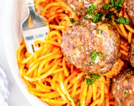 meatballs on top of pasta in white bowl