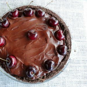 chocolate covered pie with fresh cherries arranged on top