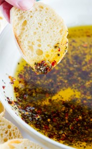 hand dipping bread into oil and herbs