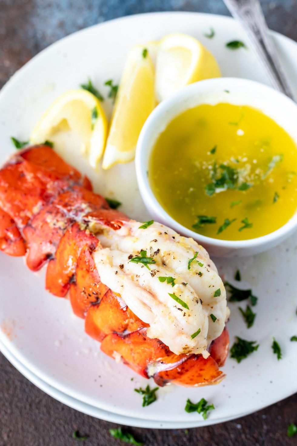 cooked lobster tail and melted butter served on white plate