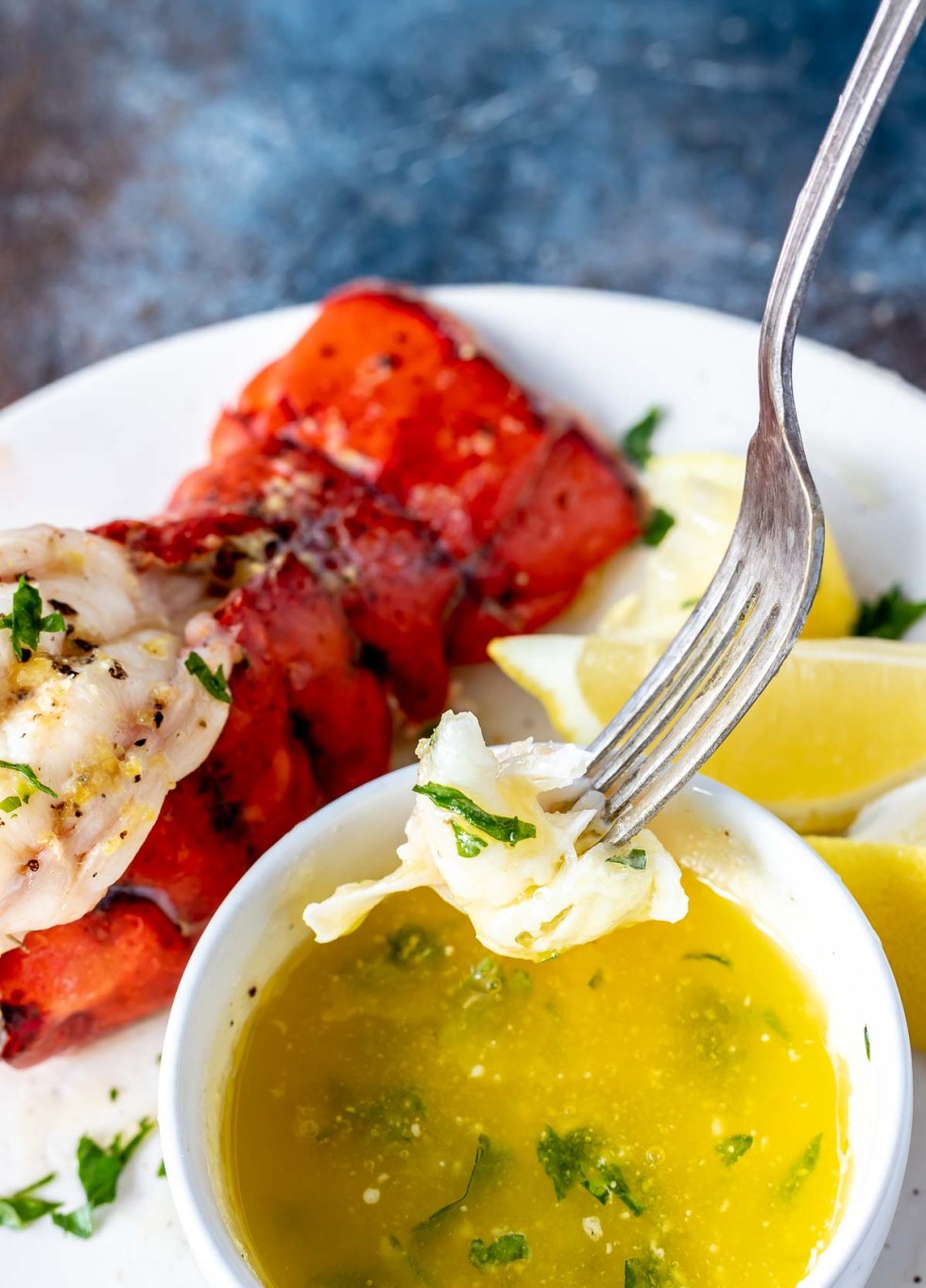 fork dipping lobster meat into melted butter