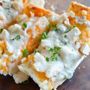 Buffalo Chicken Cheesy Bread is an easy and flavorful game day appetizer! Buffalo wing sauce, chicken and blue cheese come together in this hot, melty cheesy bread recipe.