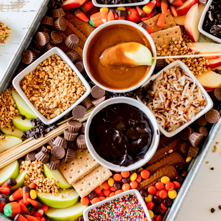 board filled with candy dips and sliced apples