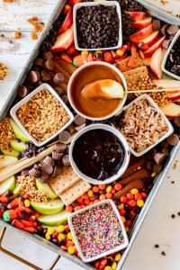 board filled with candy dips and sliced apples