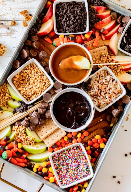 board filled with candy dips and sliced apples