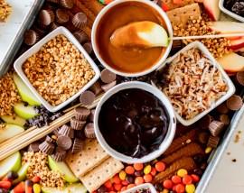 board filled with candy dips and sliced apples