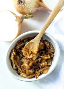 white bowl filled with caramelized onions and a mini bamboo serving spoon