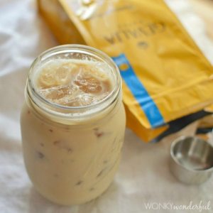 glass mason jar filled with creamy iced coffee next to yellow coffee package