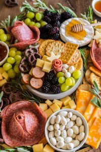 meats cheeses and fruits arranged on a wooden board