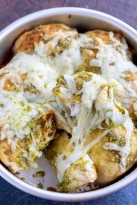 baked rolls topped with melted cheese and pesto