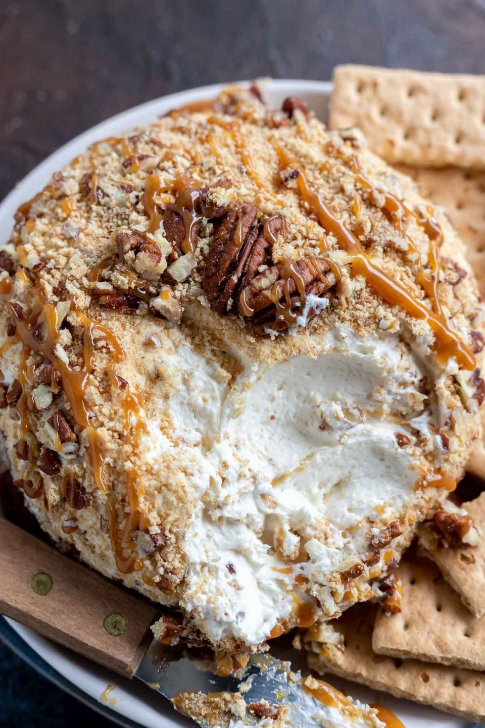 cream cheese ball covered with graham cracker crumbs, chopped pecans and caramel