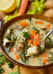 spoon scooping soup out of brown bowl