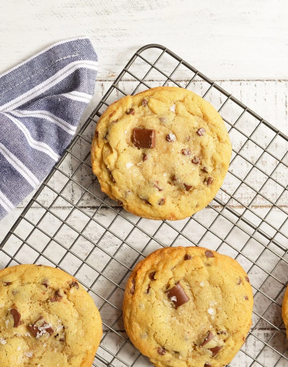 These Soft Chocolate Chip Cookies are my family's favorite treat! A special secret ingredient gives them a unique flavor and they are loaded with two types of chocolate chips! Also, this is a High Altitude Chocolate Chip Cookies Recipe. Soft, chewy, super-chocolaty and finished with a sprinkle of sea salt. #chocolatechipcookies #chocolatechipcookierecipes 