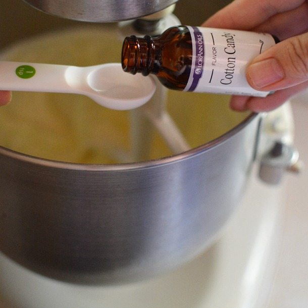 hand pouring cotton candy flavoring into measuring spoon