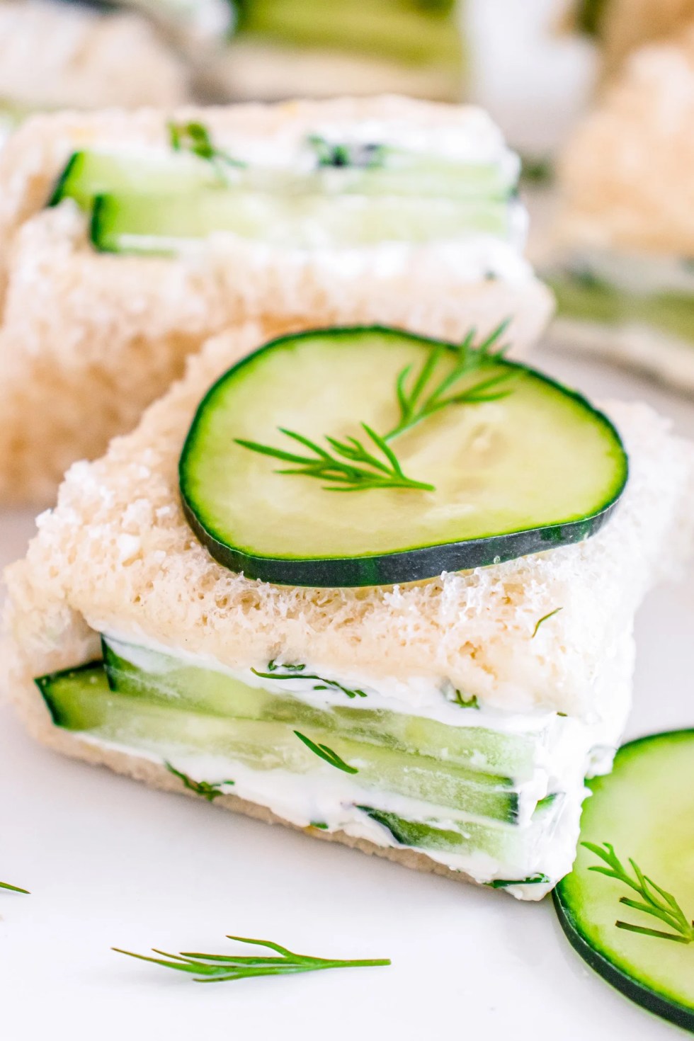 sandwich square topped with sliced cucumber and fresh dill