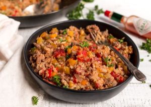 close up photo of cajun dirty rice in black bowl with fork