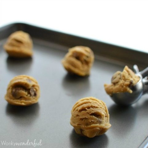 round raw cookie dough balls on rimmed baking sheet