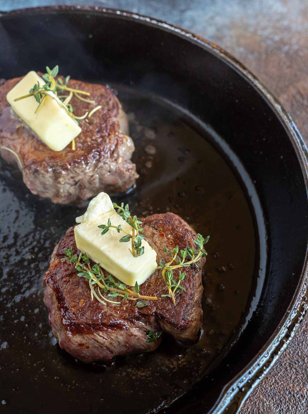 steaks topped with butter cubes and fresh thyme