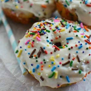 donuts topped with white glaze and colorful rainbow sprinkles