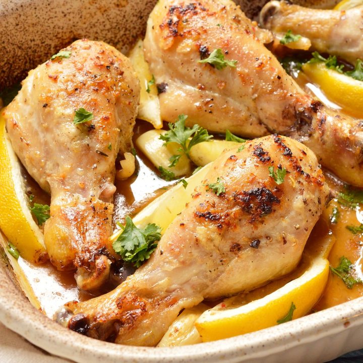 closeup of chicken drumsticks in white roasting dish