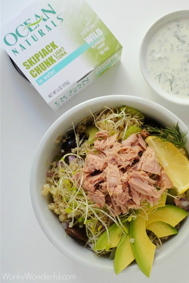 tuna, avocados, sprouts and quinoa in white bowl next to package of canned tuna