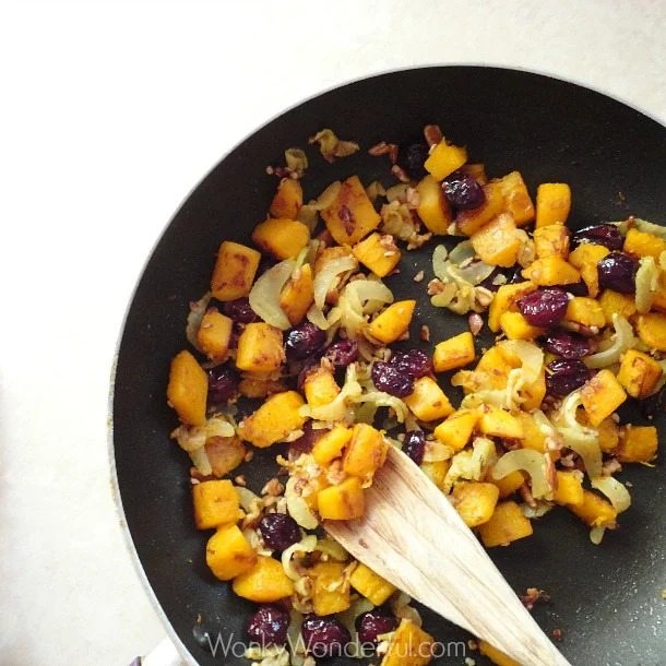 pumpkin, celery and cranberries in pan with wooden spoon