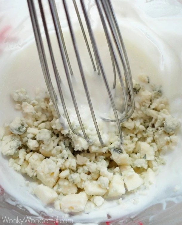 whisk in bowl with cream and crumbly cheese