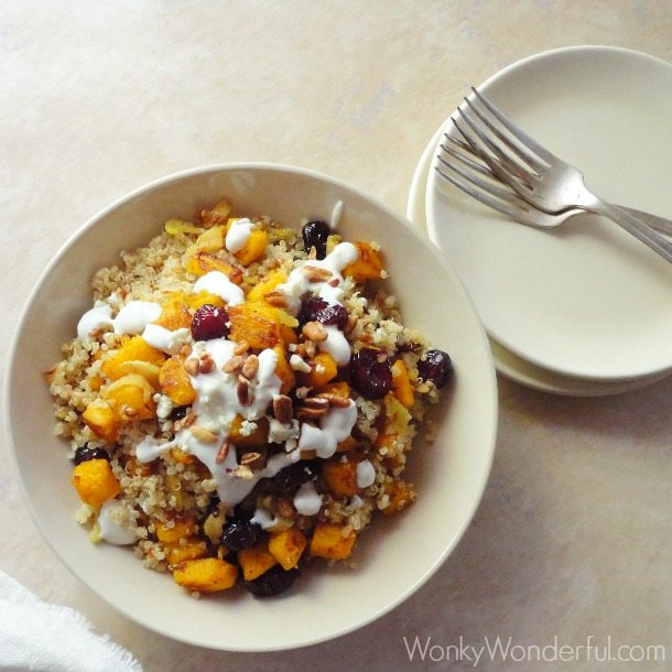 quinoa, pumpkin and cranberries in beige bowl next to plates and forks