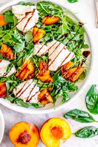 burrata, peaches and arugula on white plate