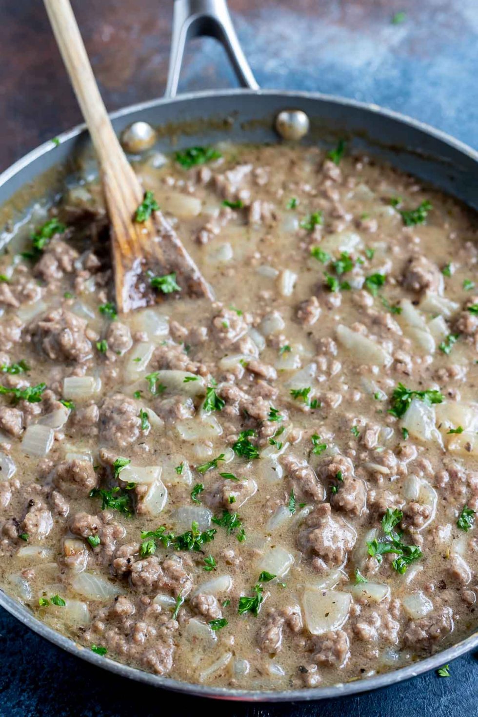 cooked ground beef gravy in fry pan with wooden spoon