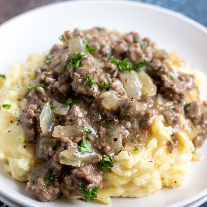 mashed potatoes topped with ground beef gravy served on white plate