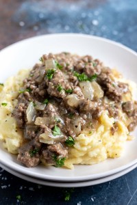 mashed potatoes topped with ground beef gravy served on white plate