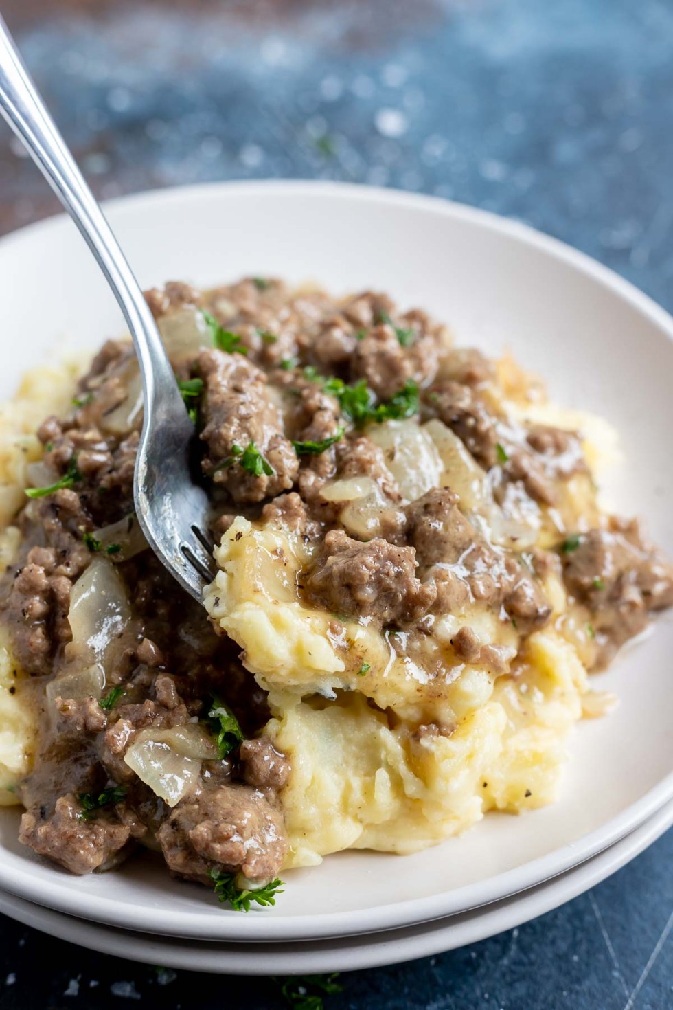 mashed potatoes and gravy on white plate with fork scooping bite