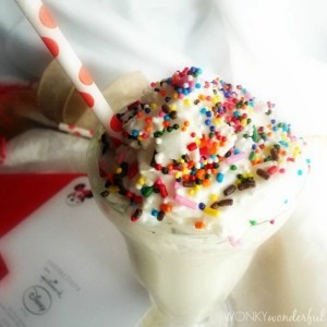 milkshake topped with rainbow sprinkles and red polka dot straw