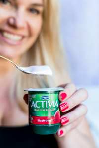 blonde lady holding strawberry yogurt with red painted nails