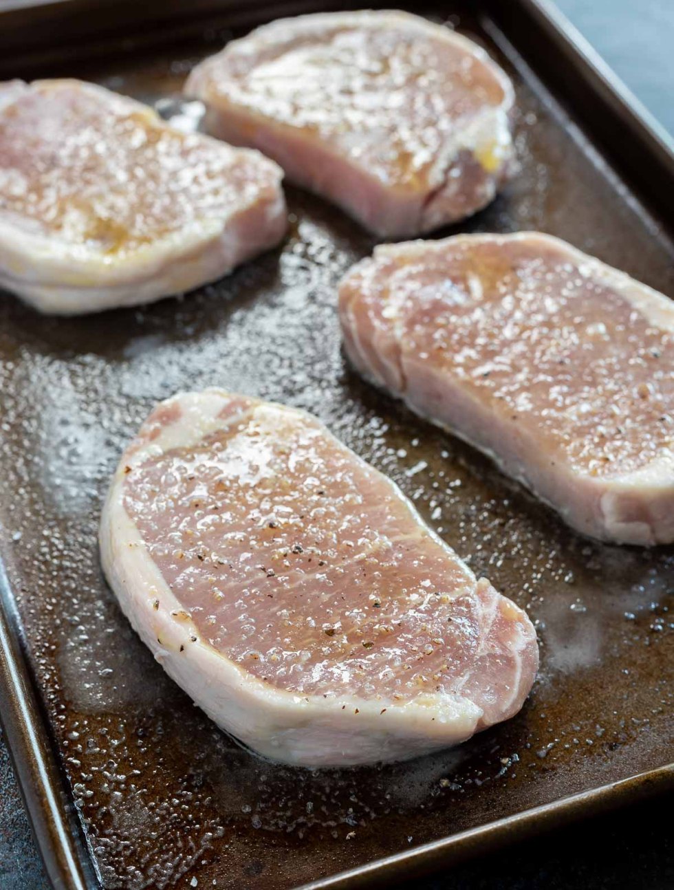 raw pork chops on rimmed baking sheet