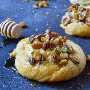 Do you want to make an amazing breakfast pastry without all the fuss? This Honey Nut Cream Cheese Danish Recipe is unbelievably simple. Use crescent rolls as a shortcut then fill with orange infused cream cheese, top with honeyed walnuts and pistachios.