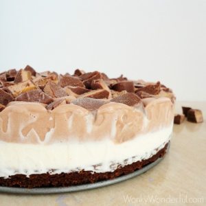 closeup of pie with brownie layer, vanilla ice cream and chocolate ice cream layers topped with candy bars