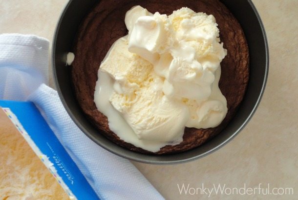 white ice cream on top of cooked brownies in round pan