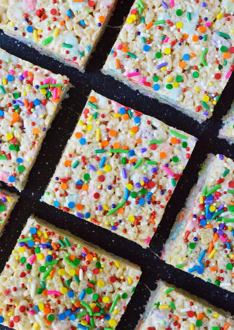 These Magical Rainbow Rice Crispy Treats are perfect for a surprise treat or a colorful unicorn party! This easy dessert recipe makes super chewy krispy treats full of magical charm marshmallows. Top them with rainbow sprinkles for the ultimate kid approved treat!