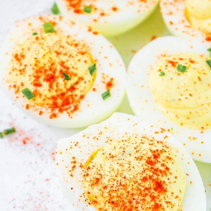 golden deviled eggs topped with red spice and chives