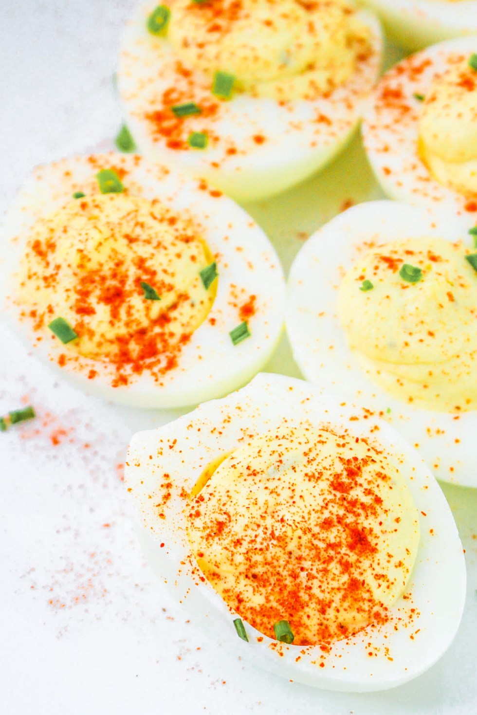 golden deviled eggs topped with red spice and chives