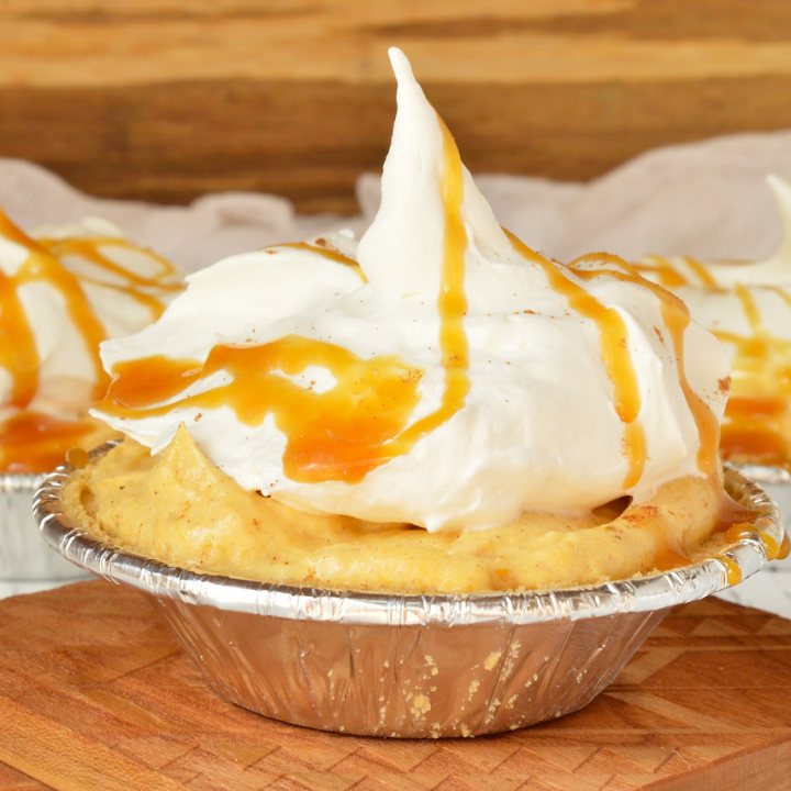 mini pumpkin cream pies topped with whipped cream and caramel sauce