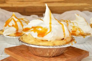 mini pumpkin cream pies topped with whipped cream and caramel sauce