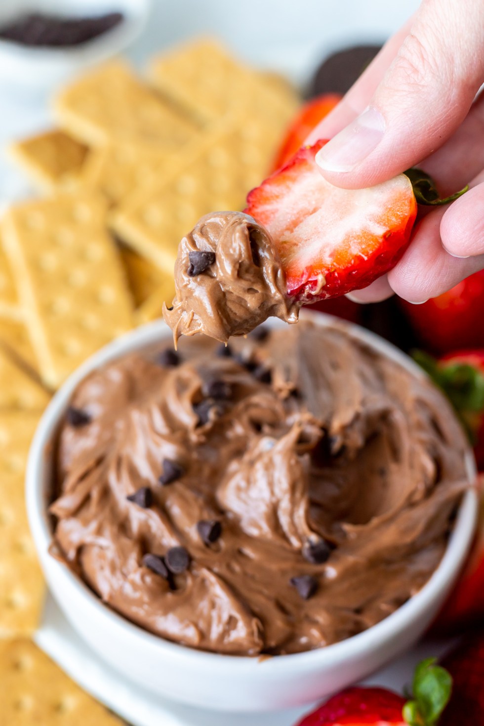 hand dipping strawberry into dip