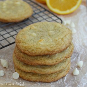 stack of golden cookies next to white chocolate chips and cooling rack